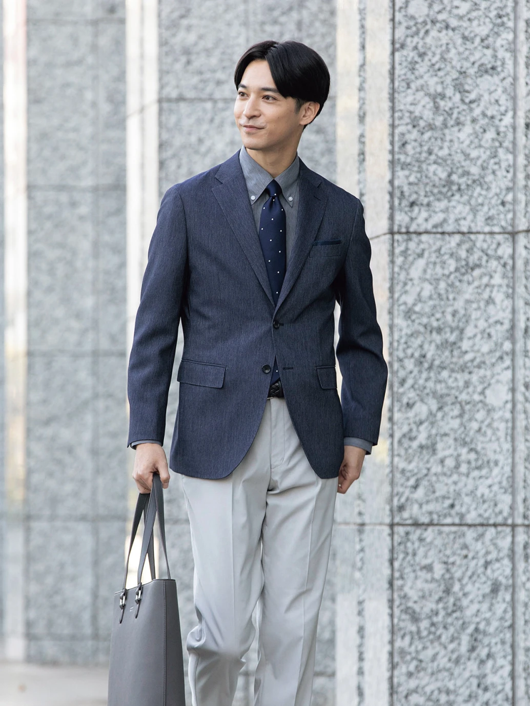 紺のジャケットに明るいグレーのスラックスを合わせた男性
